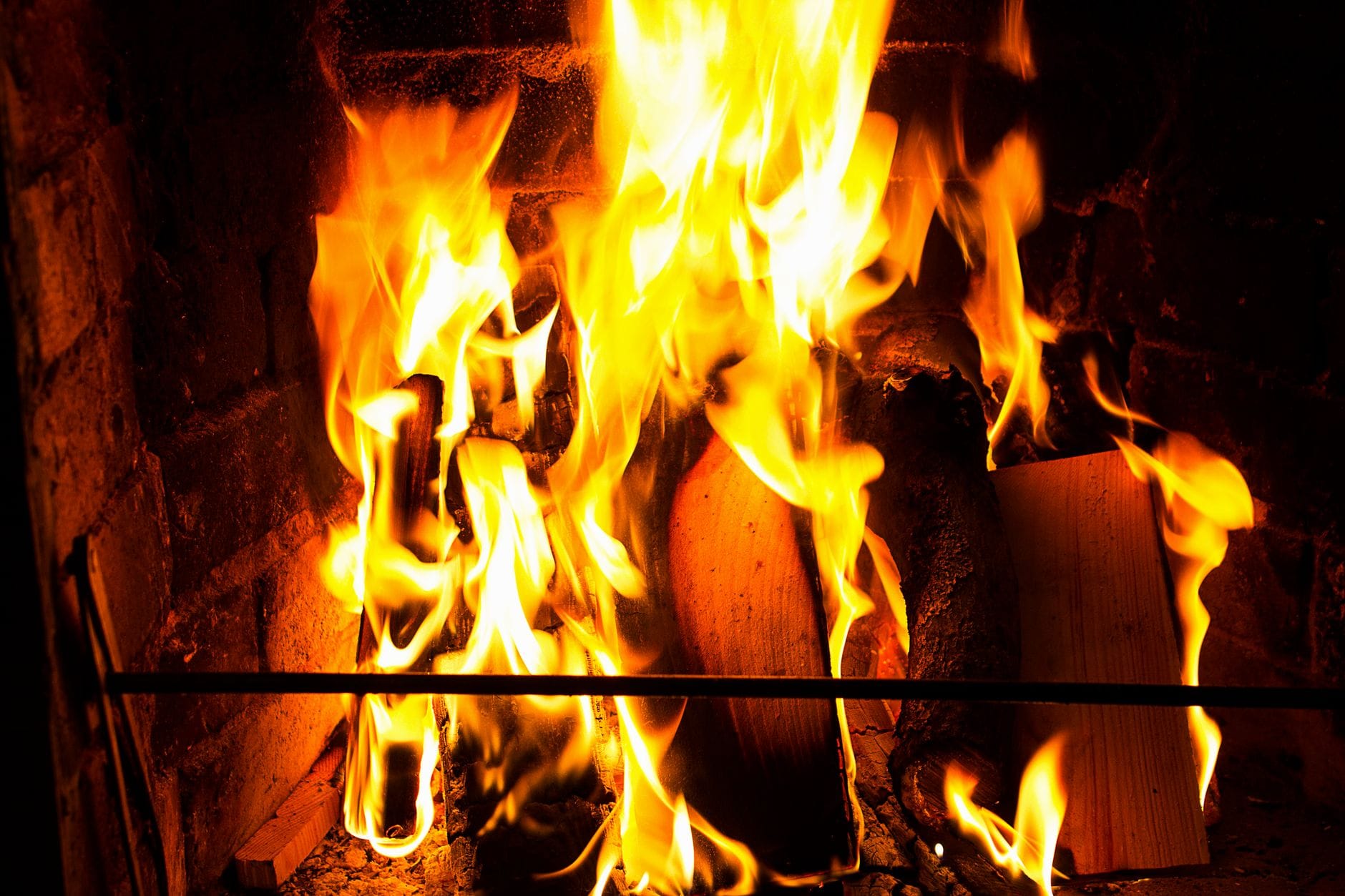 Bright flames consuming firewood in a brick fireplace, radiating warmth and comfort.